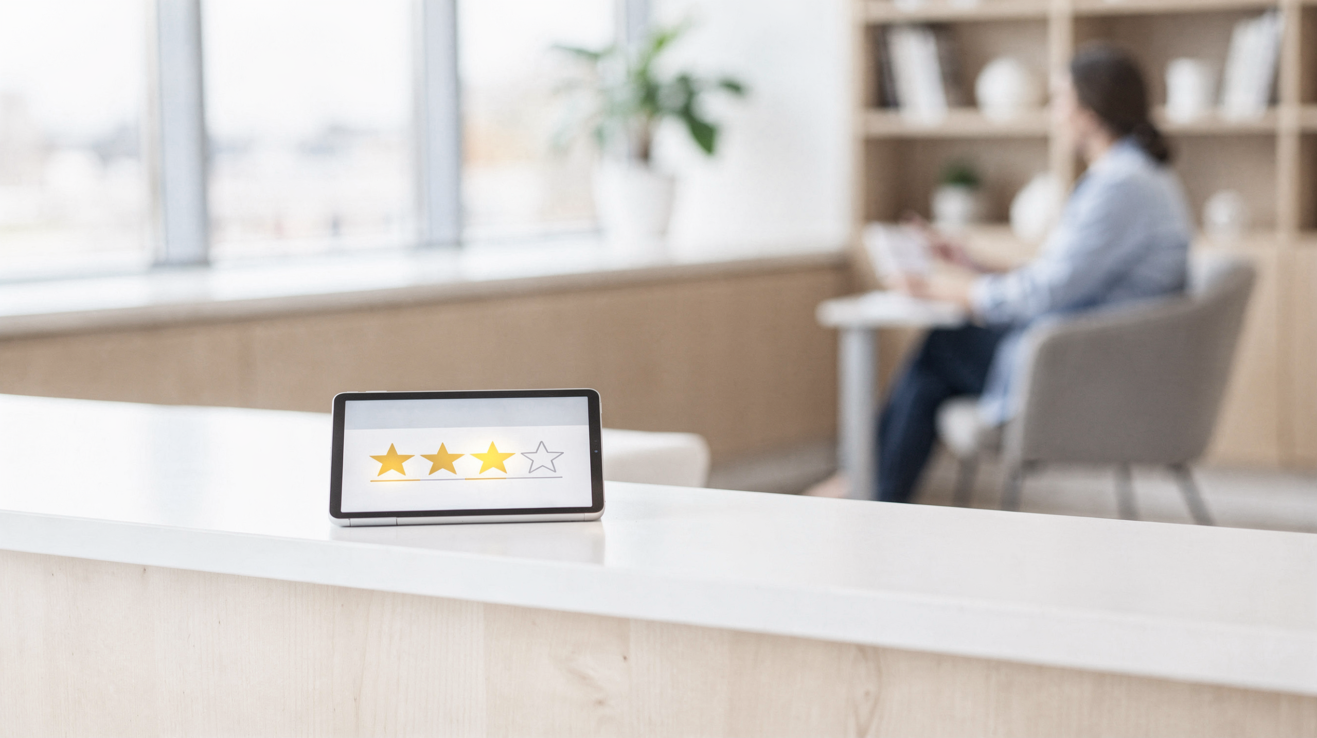 Three-star rating displayed on tablet at reception desk with patient in background at Spravato treatment clinic